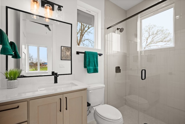 bathroom with a shower with door, vanity, and toilet