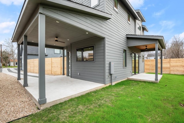 rear view of property with ceiling fan, a yard, and a patio area