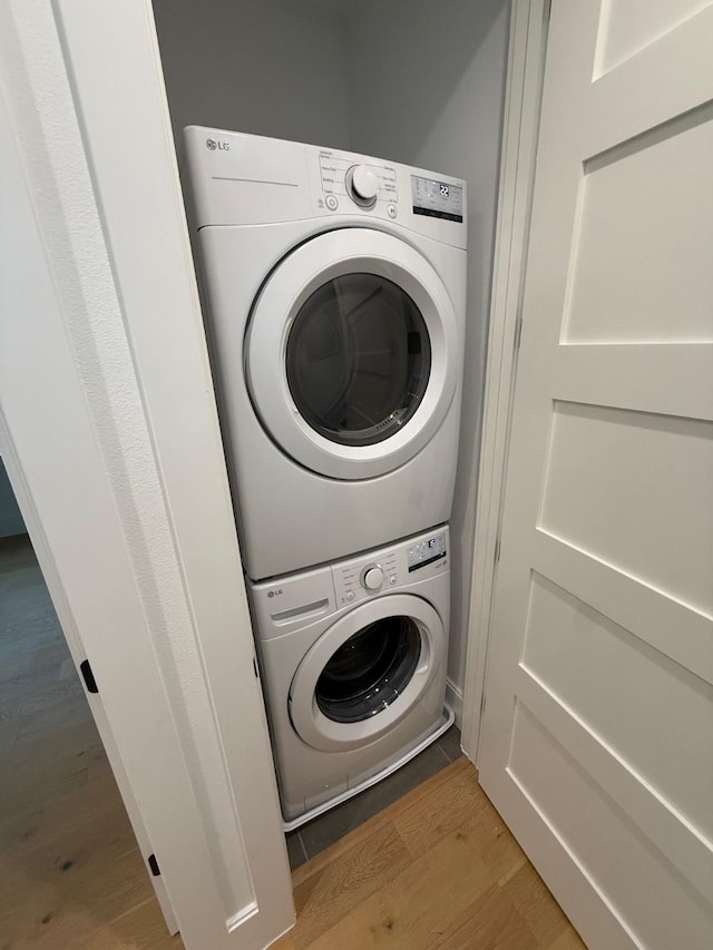 washroom with wood-type flooring and stacked washer / dryer