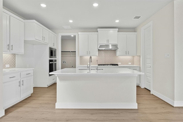 kitchen with sink, a center island with sink, white cabinets, and light hardwood / wood-style flooring