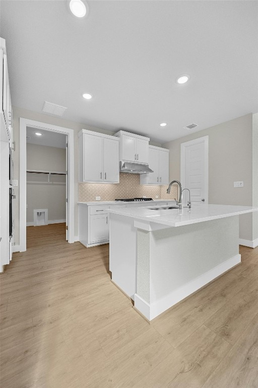 kitchen featuring white cabinetry, sink, an island with sink, and light hardwood / wood-style floors
