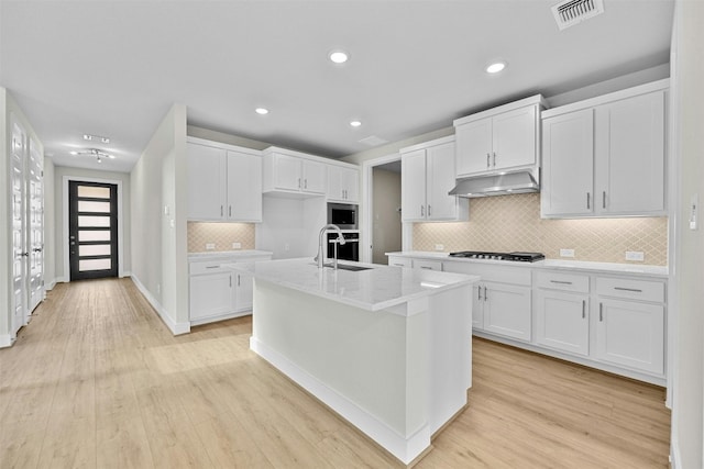 kitchen with light hardwood / wood-style floors, white cabinetry, a kitchen island with sink, and appliances with stainless steel finishes