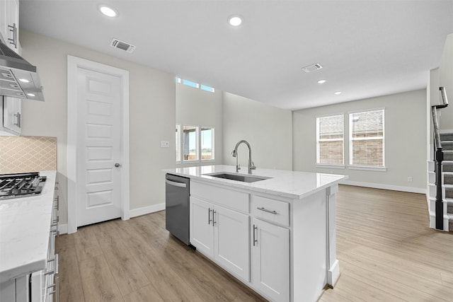 kitchen featuring a kitchen island with sink, white cabinets, sink, light stone countertops, and stainless steel appliances