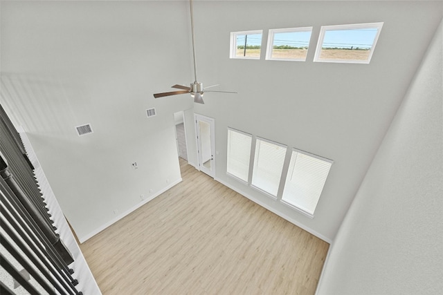 unfurnished living room featuring a high ceiling, light hardwood / wood-style flooring, and ceiling fan