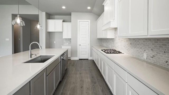 kitchen featuring appliances with stainless steel finishes, dark wood-type flooring, sink, decorative light fixtures, and white cabinetry