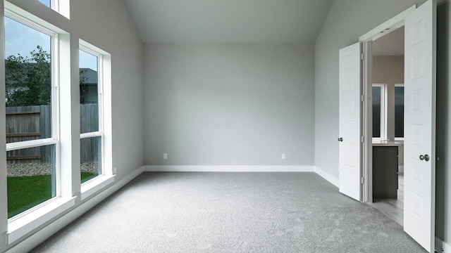 carpeted spare room featuring a wealth of natural light and vaulted ceiling