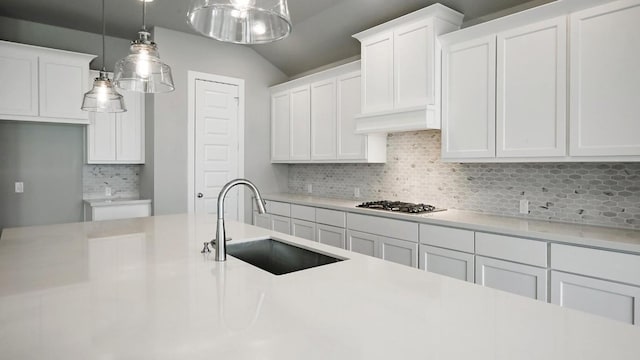 kitchen with pendant lighting, backsplash, white cabinetry, and sink