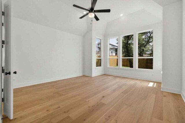 empty room featuring light hardwood / wood-style floors, vaulted ceiling, and ceiling fan