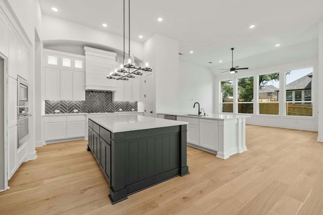 kitchen with tasteful backsplash, white cabinets, stainless steel appliances, light hardwood / wood-style floors, and pendant lighting