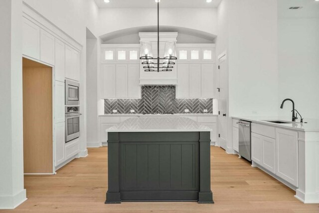 kitchen featuring decorative backsplash, stainless steel appliances, hanging light fixtures, and light wood-type flooring