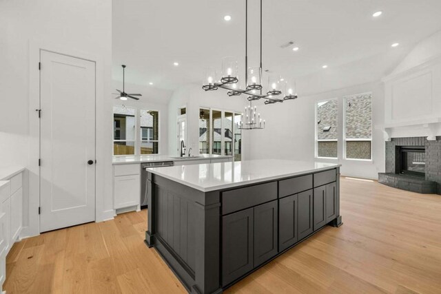 kitchen with light hardwood / wood-style flooring, a center island, a wealth of natural light, and ceiling fan with notable chandelier