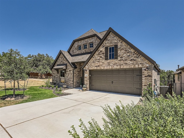 view of front facade featuring brick siding, fence, driveway, and a garage