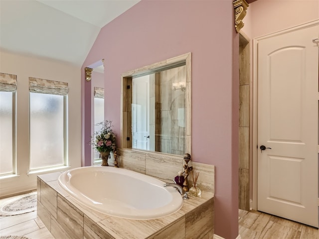 full bath featuring wood finished floors, vaulted ceiling, and a garden tub