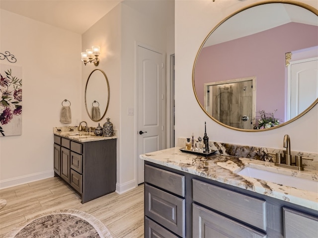 full bath featuring two vanities, wood finished floors, a sink, and baseboards