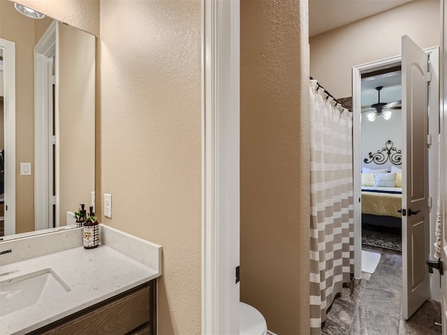 ensuite bathroom with vanity, toilet, ensuite bath, and a textured wall