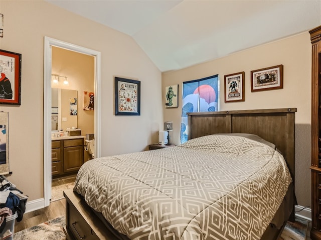 bedroom featuring ensuite bathroom, vaulted ceiling, and dark wood-type flooring