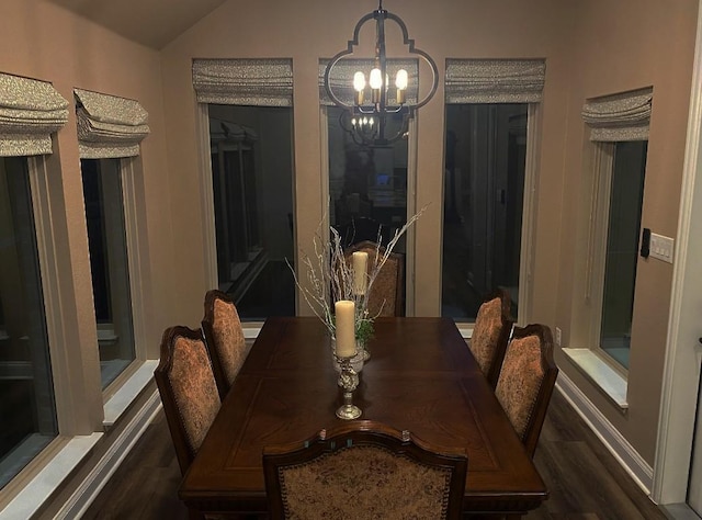 dining room with dark wood finished floors, an inviting chandelier, and vaulted ceiling