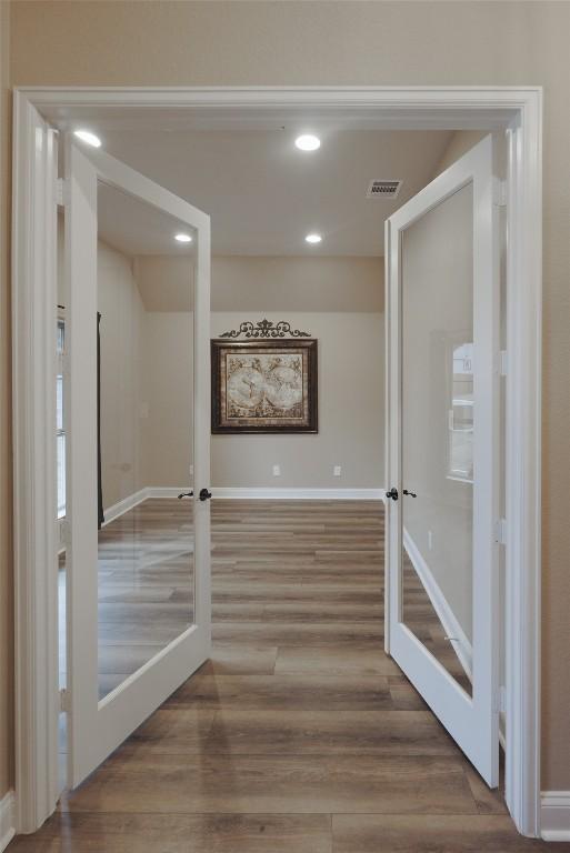 corridor featuring french doors, visible vents, baseboards, and wood finished floors