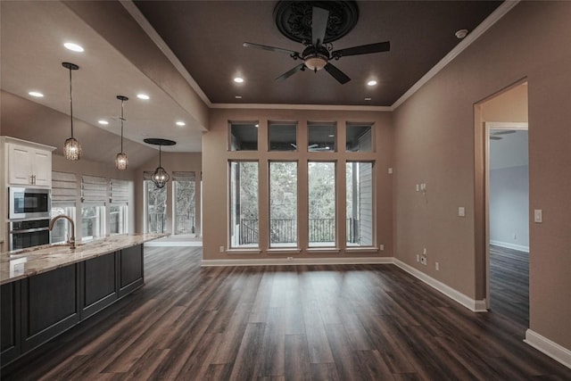 kitchen with appliances with stainless steel finishes, white cabinetry, a sink, and baseboards