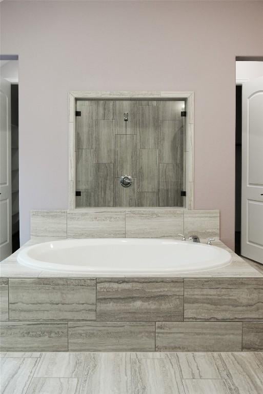 bathroom with a garden tub and a tile shower