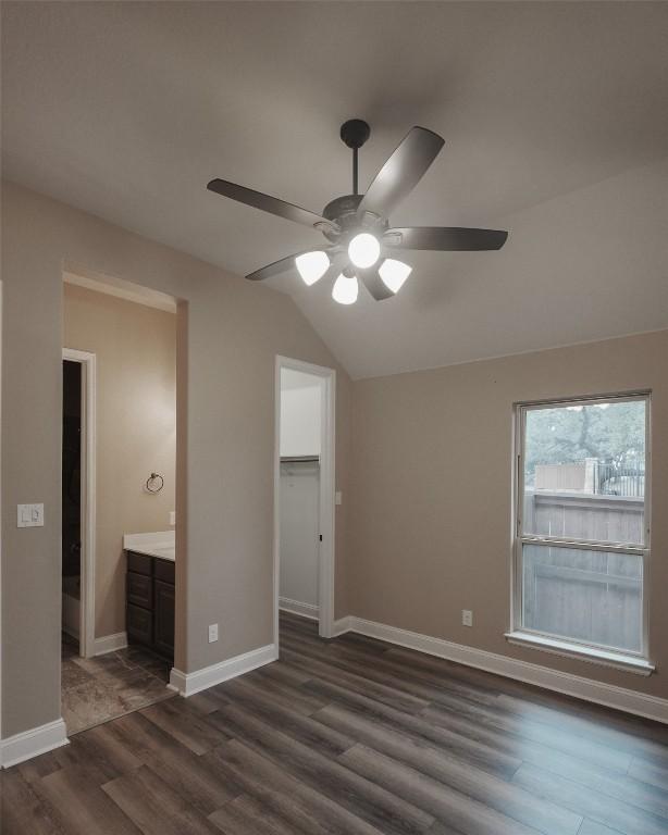 unfurnished bedroom featuring a closet, dark wood-type flooring, vaulted ceiling, ceiling fan, and baseboards