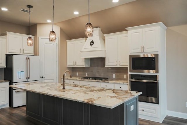 kitchen with custom range hood, black cooktop, visible vents, white fridge with ice dispenser, and oven