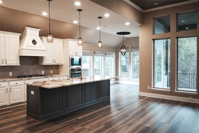 kitchen with light stone counters, stainless steel appliances, tasteful backsplash, custom range hood, and white cabinetry