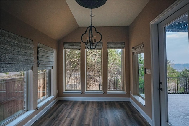 unfurnished dining area with dark wood-type flooring, lofted ceiling, baseboards, and an inviting chandelier