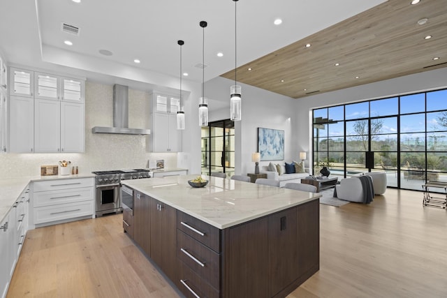 kitchen with wall chimney exhaust hood, double oven range, dark brown cabinets, and white cabinets