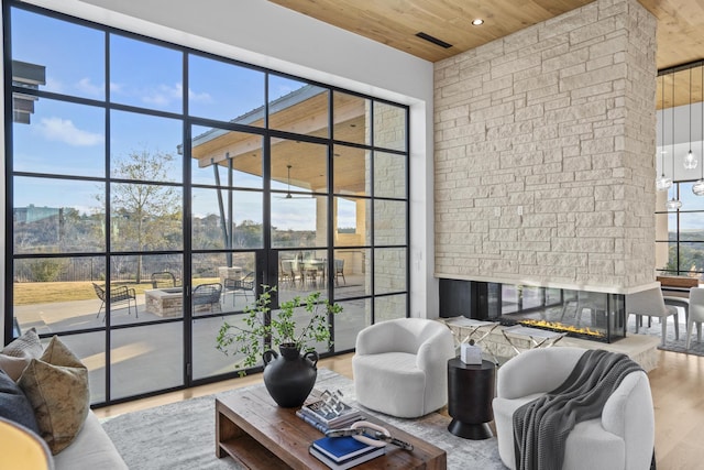 living room with hardwood / wood-style flooring, a fireplace, wooden ceiling, and a healthy amount of sunlight