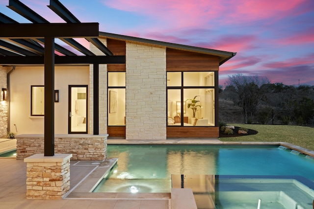 pool at dusk with an in ground hot tub