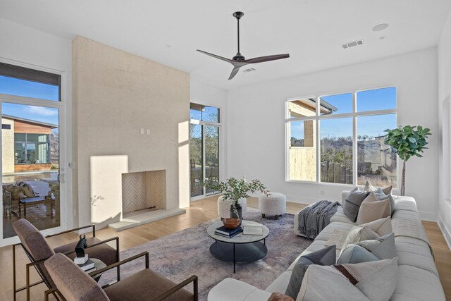 living room featuring ceiling fan, a fireplace, and light hardwood / wood-style floors