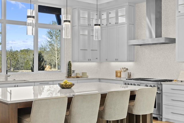 kitchen featuring a center island, wall chimney range hood, white cabinets, and high end range