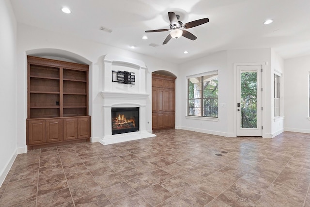 unfurnished living room featuring ceiling fan, light tile patterned floors, and built in features