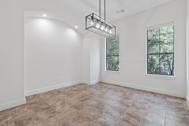 spare room with an inviting chandelier, tile patterned floors, and a healthy amount of sunlight