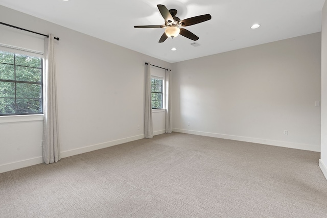 spare room featuring plenty of natural light, ceiling fan, and light colored carpet