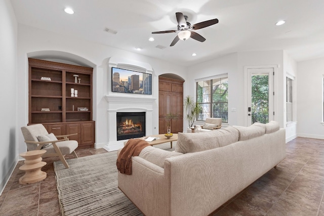 living room with ceiling fan, built in features, and tile patterned floors