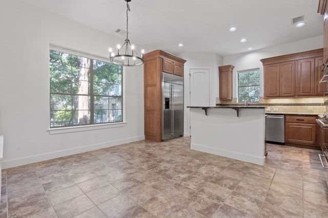 kitchen with a wealth of natural light, a kitchen breakfast bar, appliances with stainless steel finishes, and light tile patterned floors