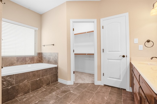 bathroom with tile floors, vanity, and tiled tub