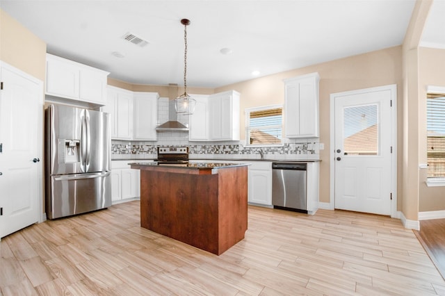 kitchen featuring white cabinets, decorative light fixtures, appliances with stainless steel finishes, and a center island