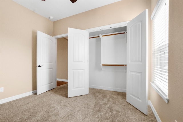 unfurnished bedroom with ceiling fan, a closet, and light carpet