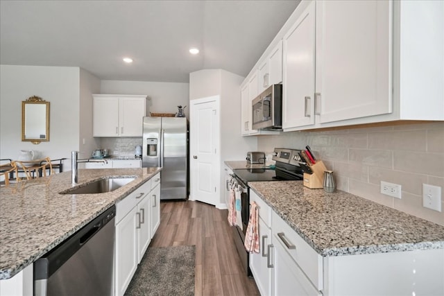 kitchen featuring dark wood-type flooring, tasteful backsplash, stainless steel appliances, and light stone counters