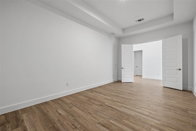 unfurnished bedroom with light hardwood / wood-style floors and a tray ceiling