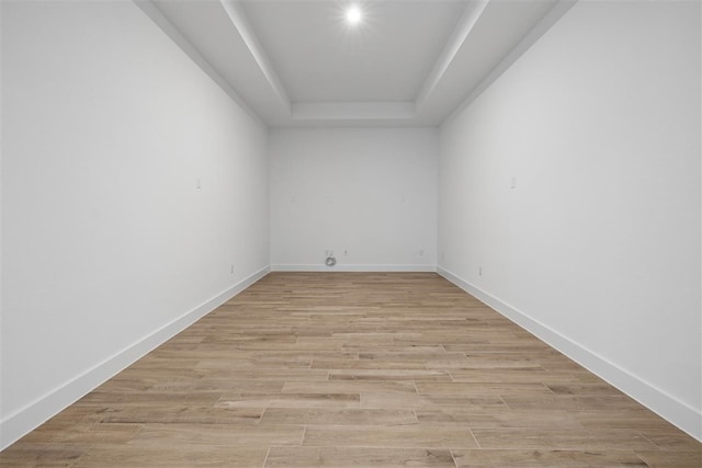 unfurnished room with light hardwood / wood-style flooring and a tray ceiling