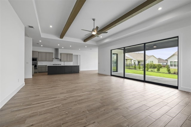 unfurnished living room with beamed ceiling, hardwood / wood-style flooring, and ceiling fan