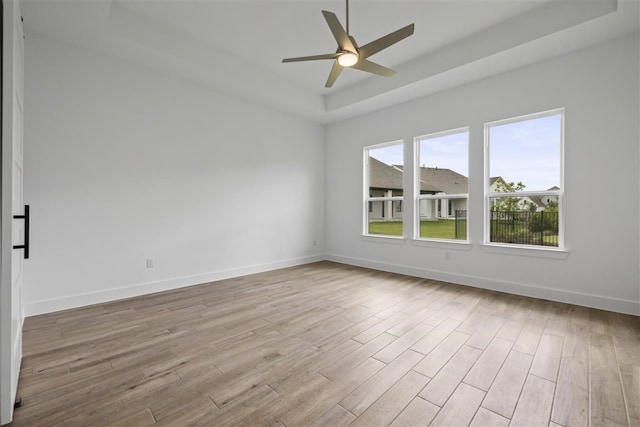 unfurnished room featuring ceiling fan, light hardwood / wood-style floors, and a raised ceiling