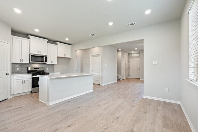 kitchen with a center island, appliances with stainless steel finishes, white cabinetry, and plenty of natural light