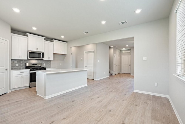 kitchen featuring white cabinetry, light hardwood / wood-style flooring, stainless steel appliances, and a kitchen island