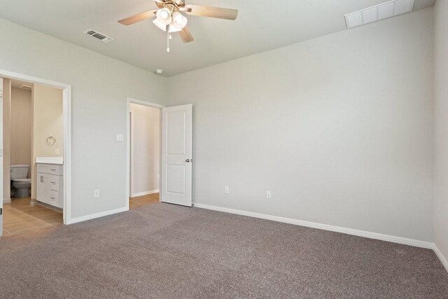 unfurnished bedroom featuring ceiling fan, light carpet, and ensuite bath