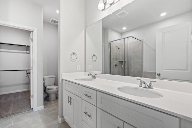 bathroom featuring toilet, vanity, tile patterned floors, and a shower with door